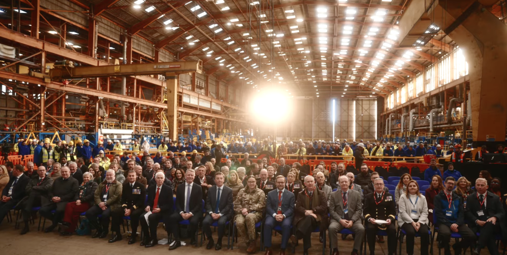Large audience seated inside a shipbuilding hall