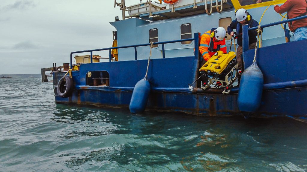 Crew deploying an ROV from a blue workboat in Portland Harbour